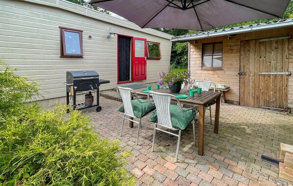 A patio with a grill, outdoor table, chairs, and a wooden door.