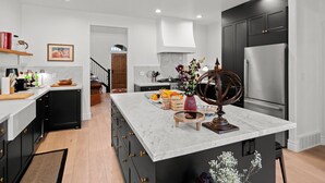 A modern kitchen with dark cabinetry, a marble countertop, and a stainless steel refrigerator. - Home in Midway - Short Drive to Deer Valley Gondola | Mountain Views | Large Deck | Private Bedrooms (Midway)