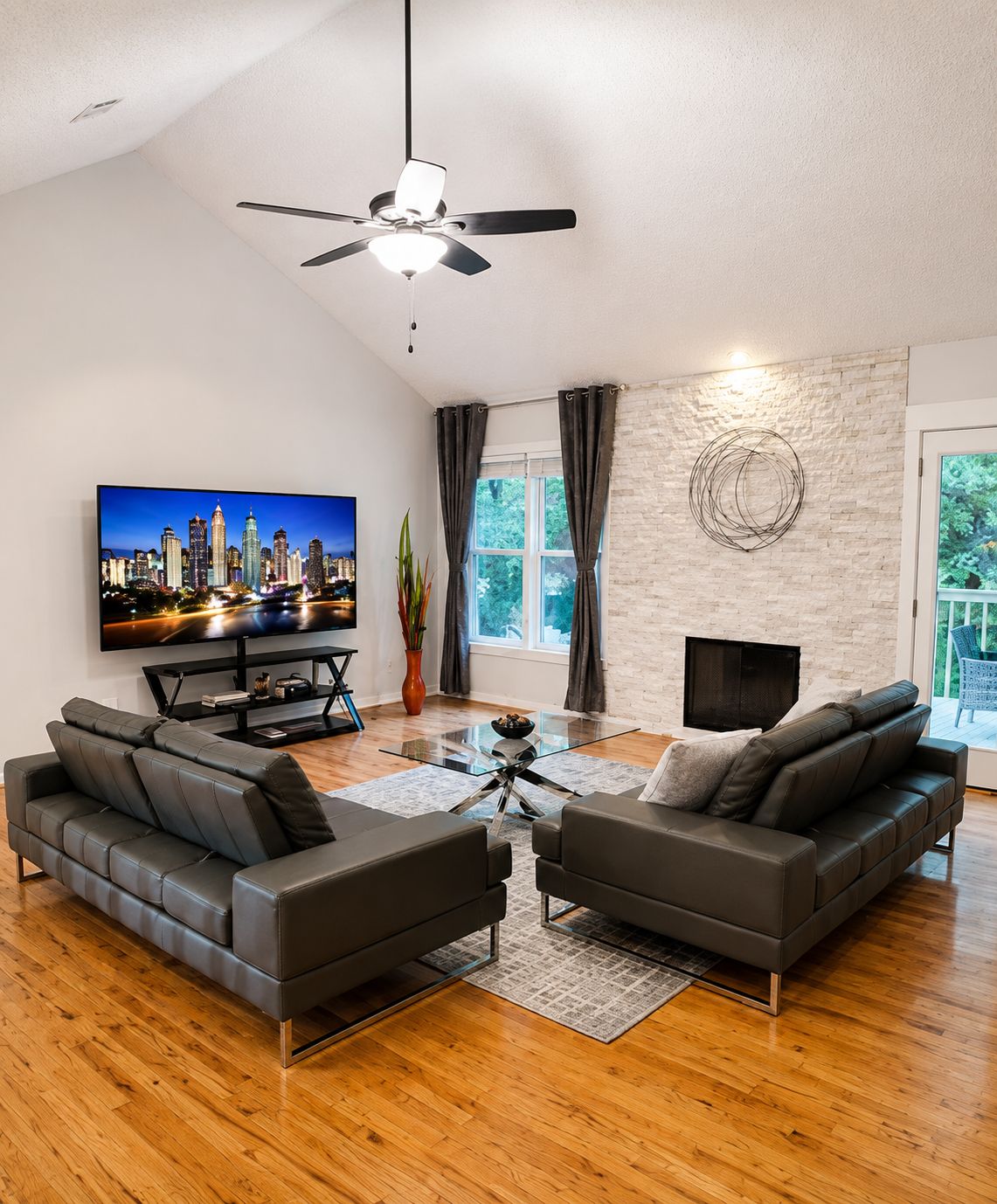 Een moderne woonkamer met een flatscreen televisie, leren banken, een glazen salontafel en een open haard.