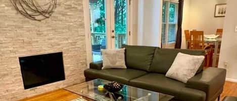 A modern living room with a glass coffee table, a sofa, and a fireplace.