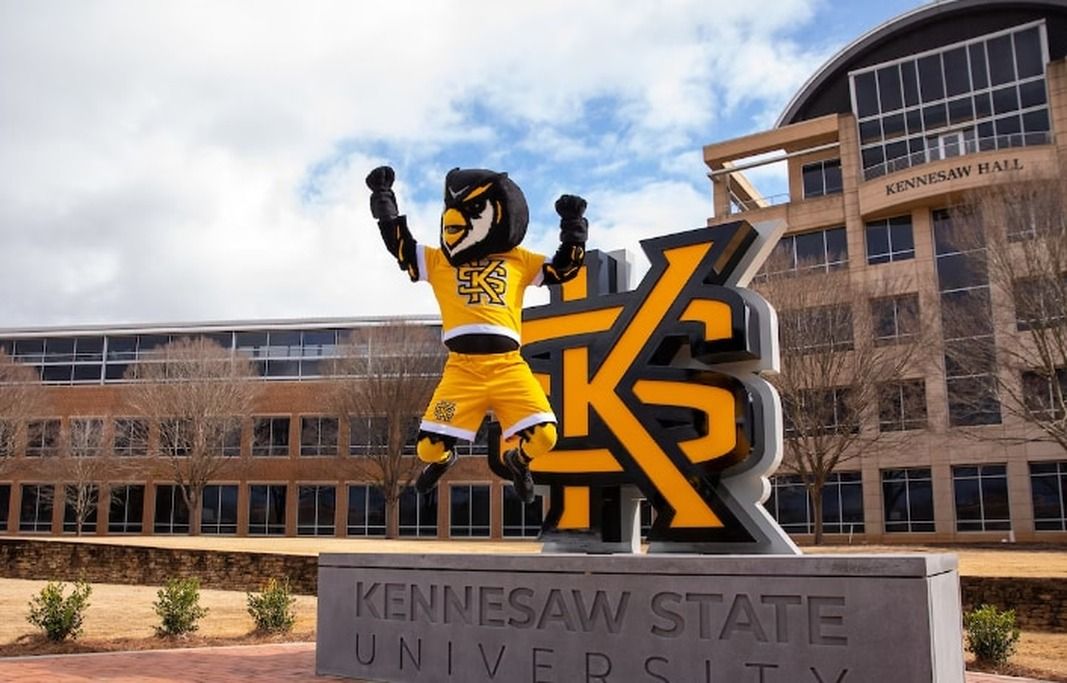 A mascot statue in front of Kennesaw State University with the building in the background.
