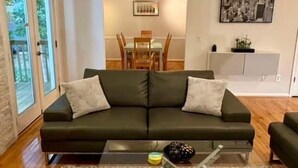 Een woonkamer met een bank, een salontafel en een eethoek op de achtergrond.