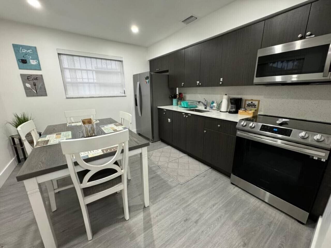 A modern kitchen with dark cabinets, a stainless steel oven, and a microwave.