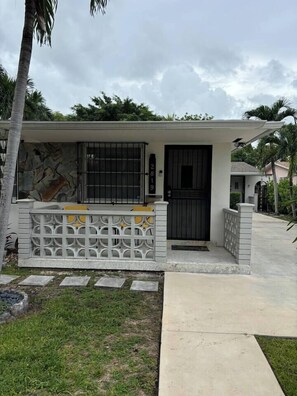 A residential house with a gated entrance, a small porch, and a concrete pathway leading to the door. - Serenity Haven 2BR|1BA | Spacious | Free Parking (Miami)