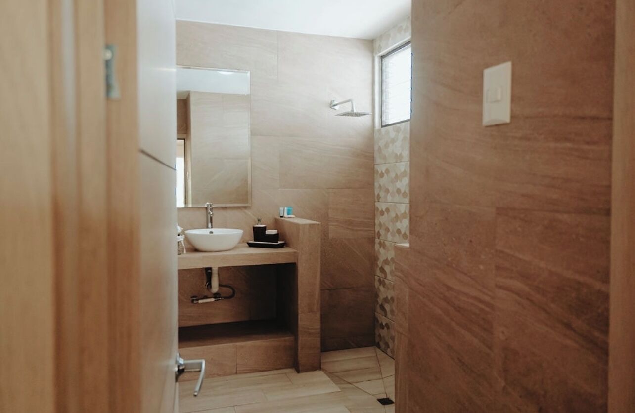A compact bathroom with a white sink, mirror, and shower.