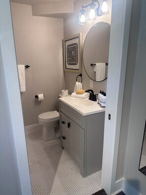 Une salle de bain équipée de toilettes, d’un lavabo, d’un miroir et d’un porte-serviettes.