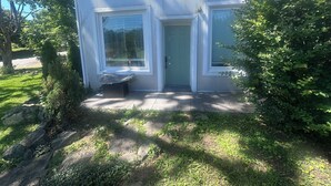 Una casa de dos pisos con puerta principal, dos ventanas y un pequeño porche.