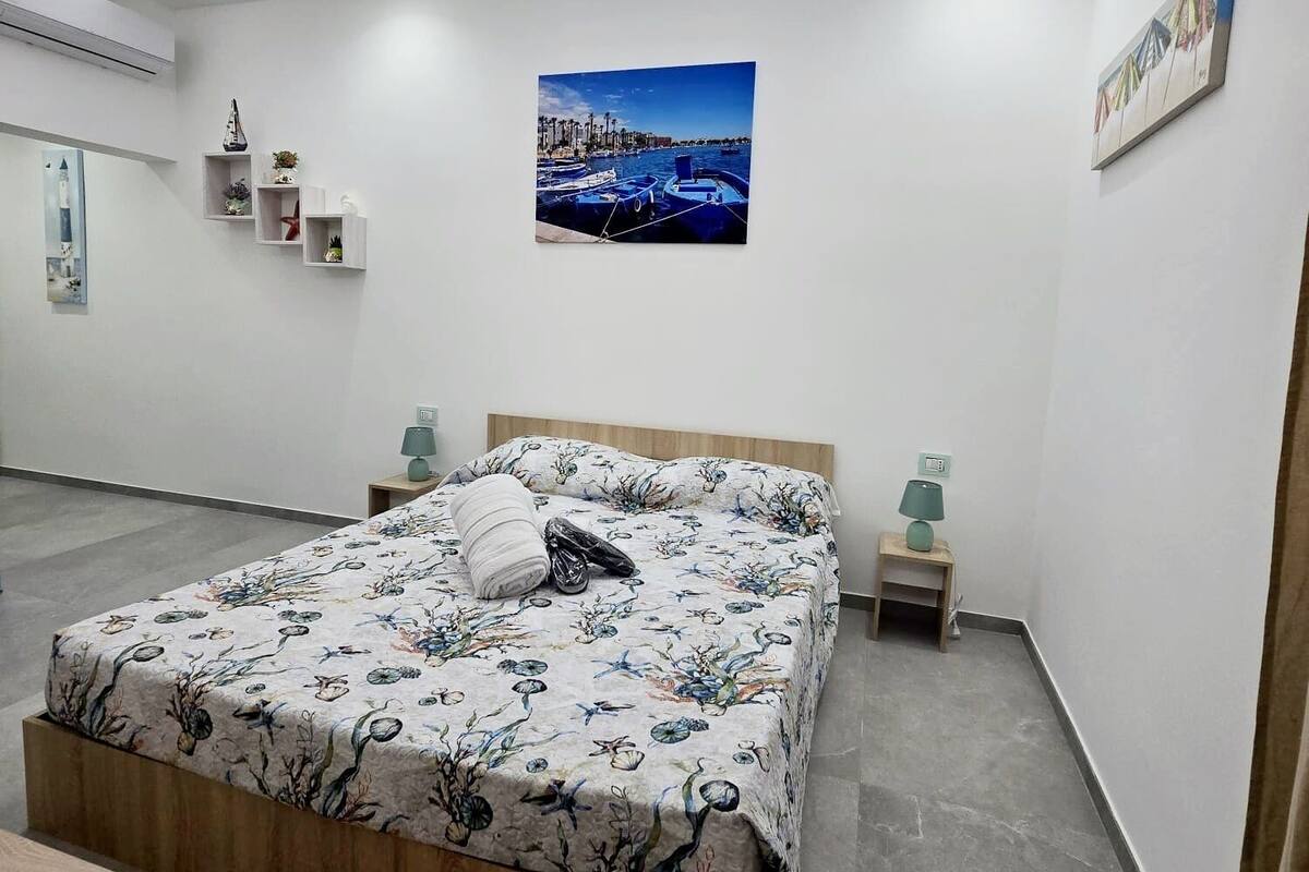 A modern bedroom with a bed, bedside tables, and a wall-mounted picture.