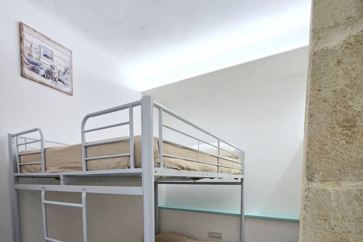 A bunk bed room with a ladder, a small shelf, and a painting on the wall.