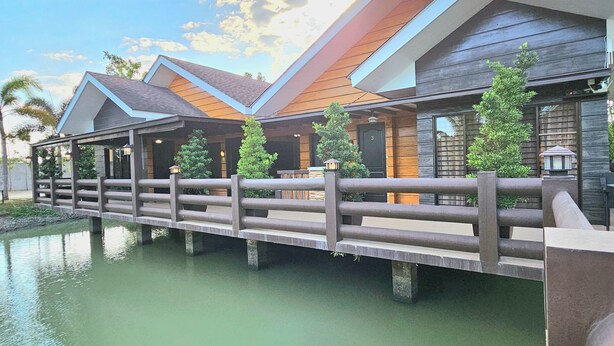 A modern hotel with a wooden facade, a bridge over a body of water, and a clear sky. - The Backyard Event and Resorts (Candaba)