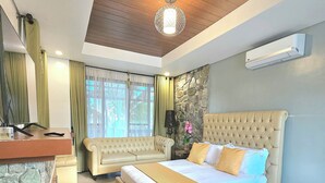 A bedroom with a large bed, a sofa, a desk, and a stone accent wall. - The Backyard Event and Resorts (Candaba)