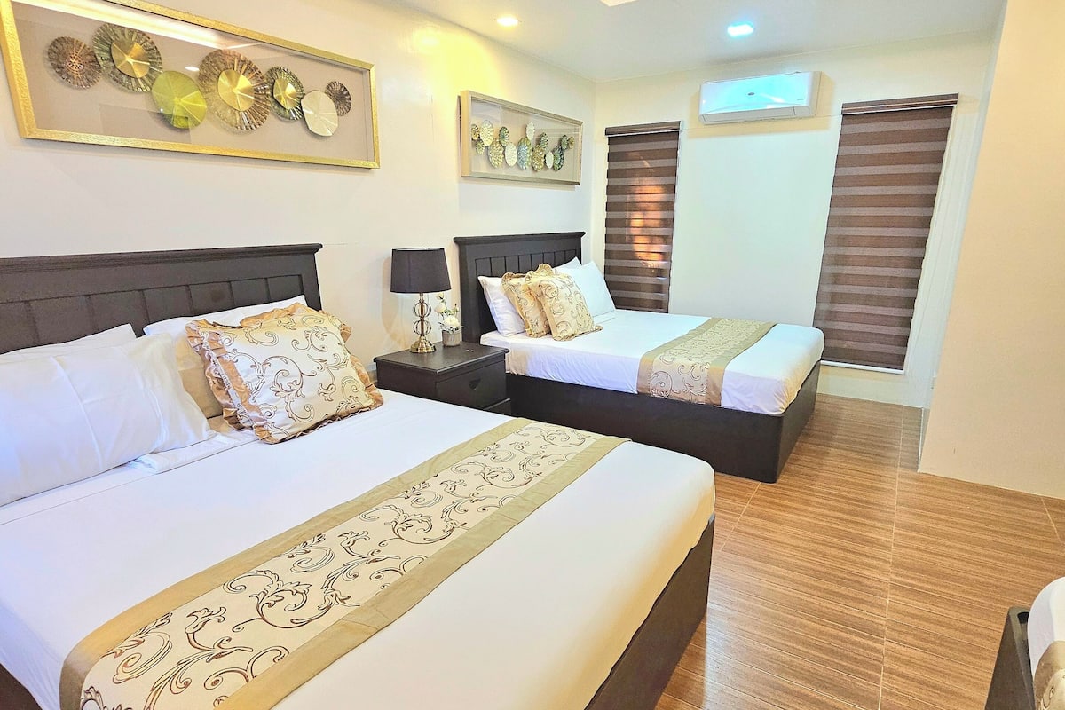 A hotel room with two beds, a wooden ceiling, and decorative wall art.