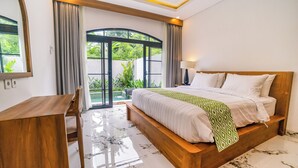 Ein Schlafzimmer mit einem hölzernen Bett, einem Schreibtisch und Blick auf Grünfläche.