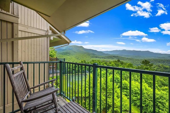 A balcony with a view of green mountains and a clear sky.