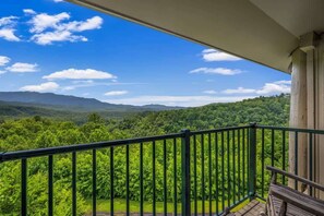 A balcony with a view of a forested mountain range.