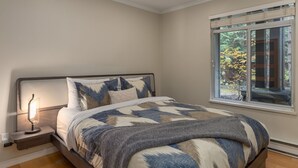 Una camera da letto con un letto, una lampada da comodino e una finestra vista alberi.