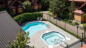 Una piscina con una piccola zona solarium, circondata da una recinzione e alberi.