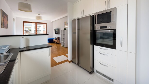Een moderne keuken met witte kasten, roestvrijstalen apparatuur en een zwart aanrecht.