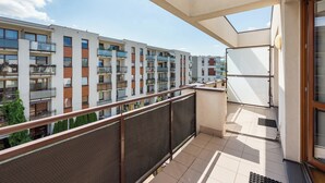 Een balkon met een metalen hekwerk dat uitkijkt op een rij moderne appartementen.