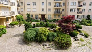 Ein Innenhof mit einem zentralen Garten, umgeben von mehrstöckigen Gebäuden mit Balkonen und Fenstern.