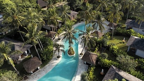 A resort with a central swimming pool surrounded by palm trees and thatched-roof structures. - Kuara Lombok (Mertak)