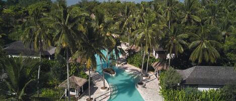 A resort with a swimming pool, palm trees, and a view of the sea.