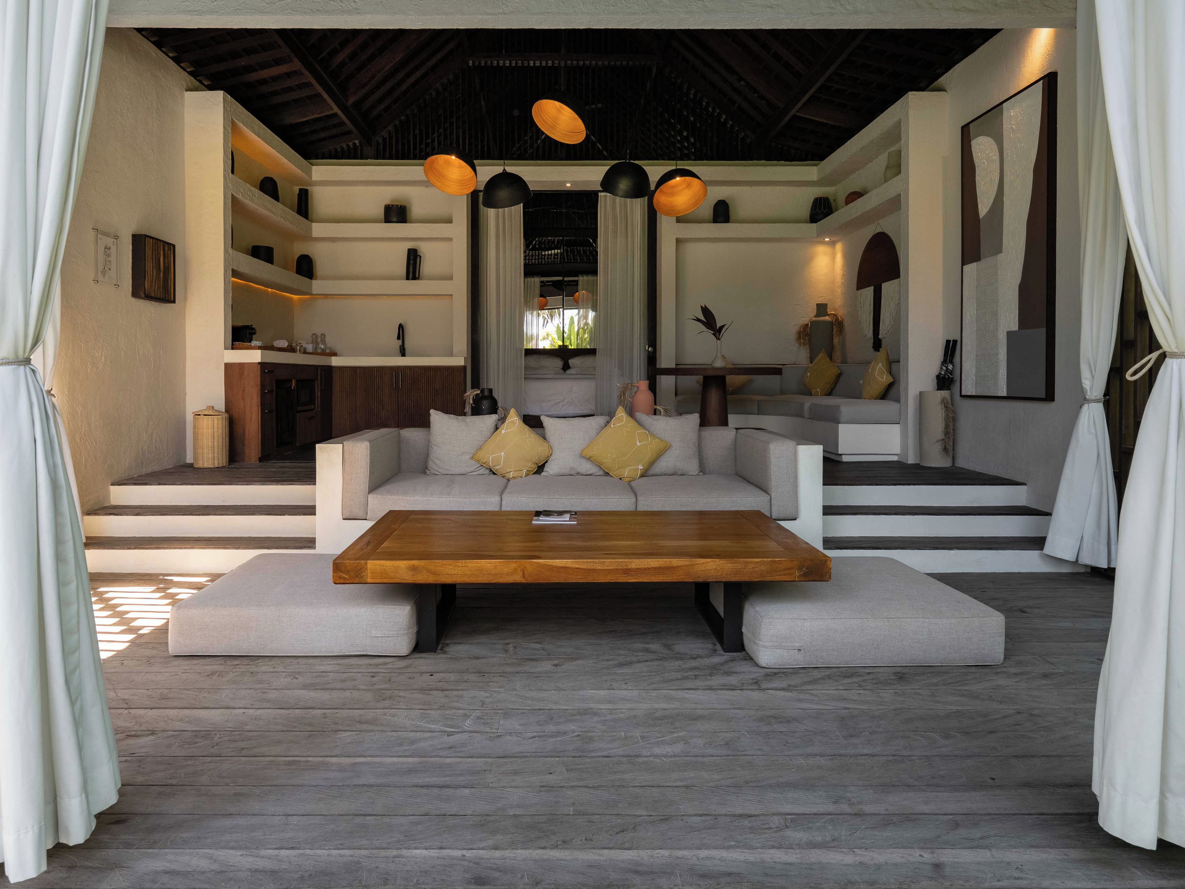 A modern living room with a sofa set, a wooden coffee table, and pendant lighting.