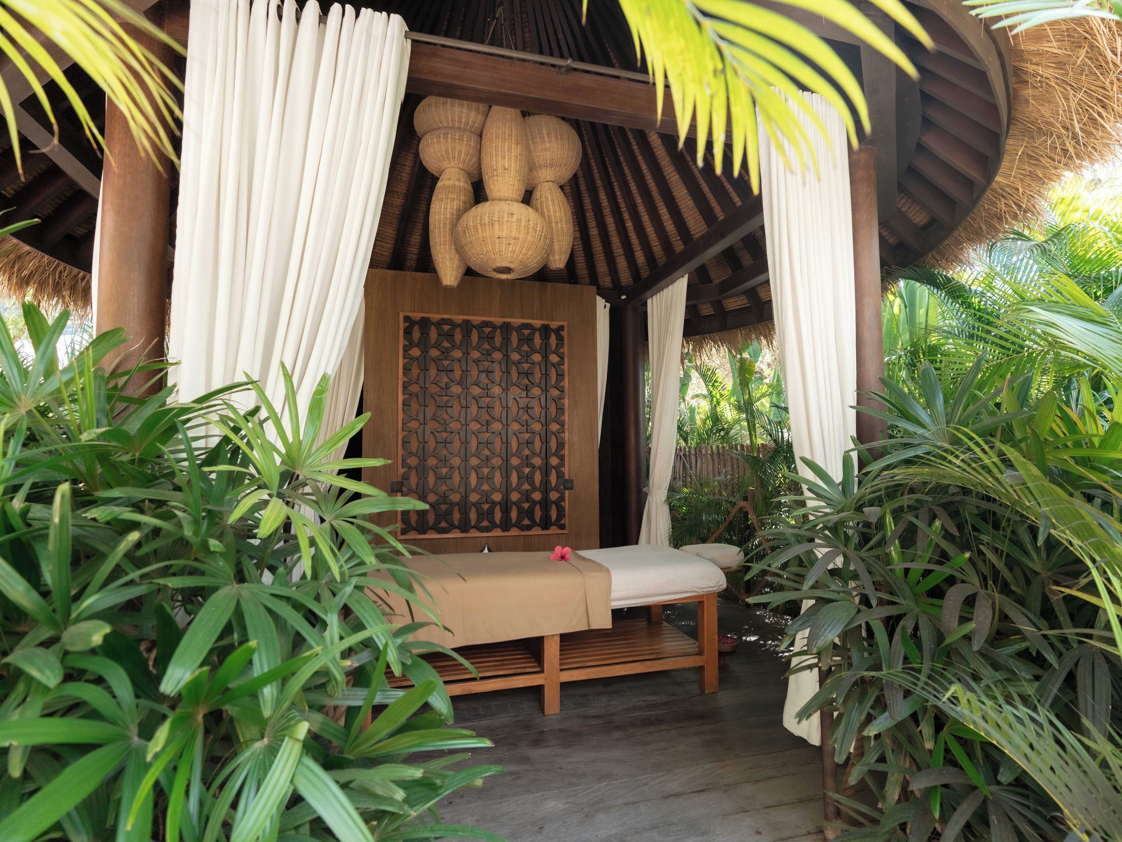 A wooden bed with a canopy, surrounded by lush green plants.