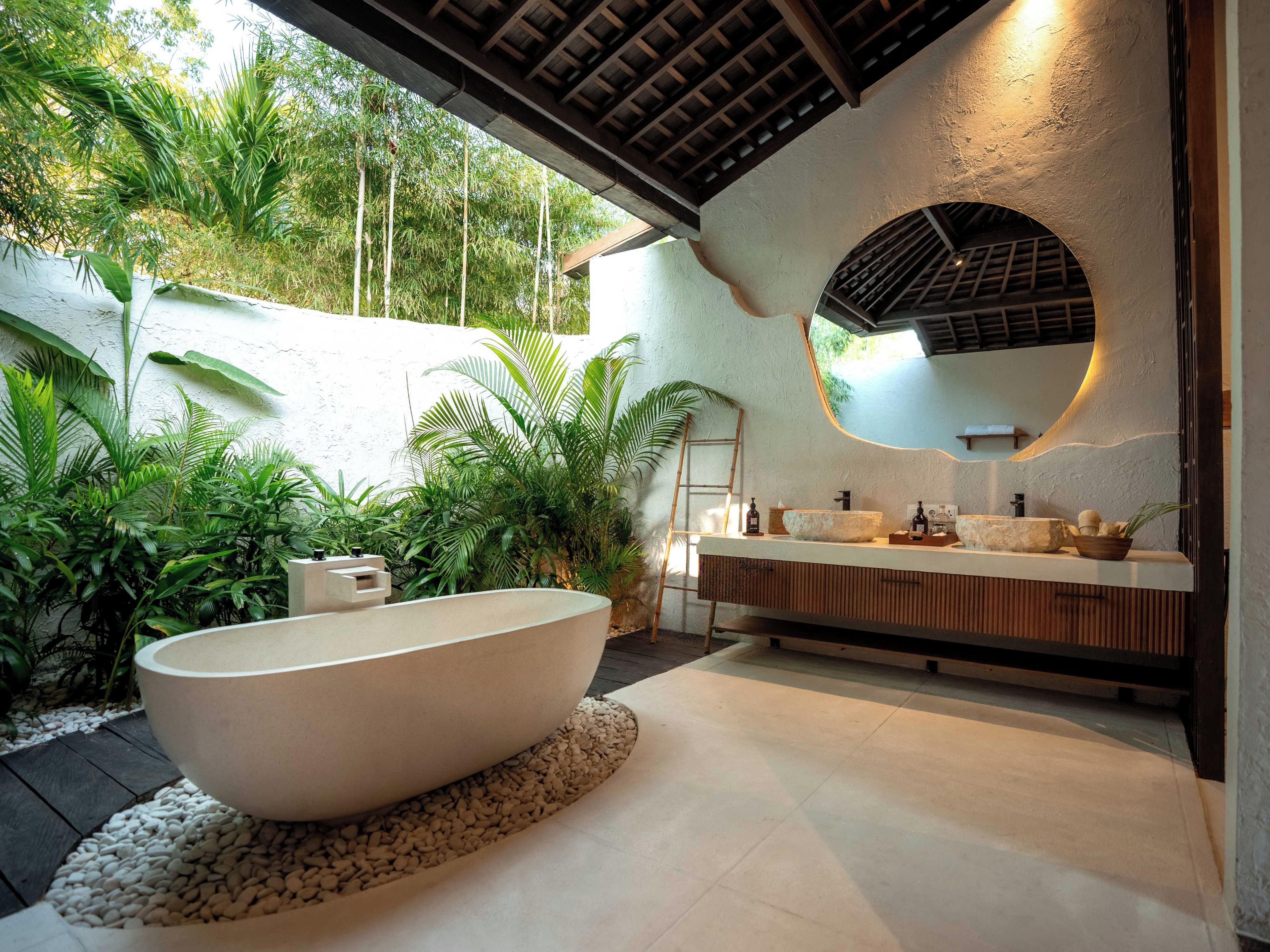Un baño moderno con una bañera independiente, un espejo grande y un lavabo con una pila de piedra.
