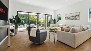 A modern living room with a sofa, armchair, coffee table, and a TV mounted on the wall.