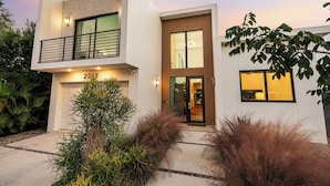 A modern two-story house with a garage, large windows, and a well-maintained garden.