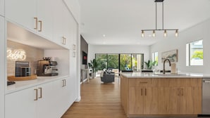 A modern kitchen with a Breville coffee machine, wooden cabinets, and a large island with a sink.
