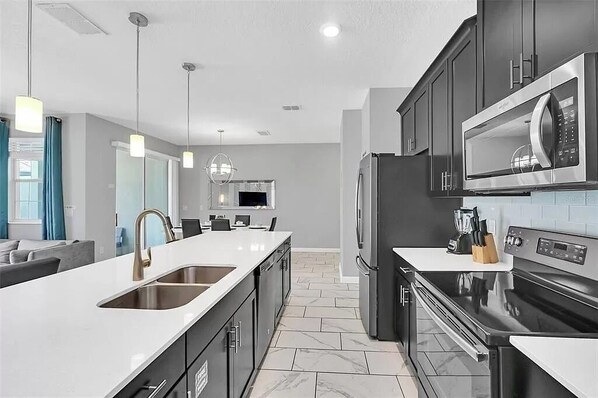 A modern kitchen with a large island, stainless steel appliances, and a dining area with a view.