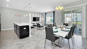 Una cocina moderna con una isla central, un comedor con una mesa dispuesta para cuatro personas y un amplio ventanal con vistas al exterior.