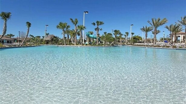Una piscina cristalina rodeada de palmeras y un tobogán.