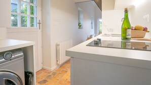 Eine moderne Küche mit eingebauter Waschmaschine, einem großen Fenster und einer Arbeitsplatte mit einer Flasche und Früchten.