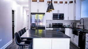 Una cocina moderna con armarios blancos, una isla central con taburetes de bar, un microondas y una estufa.