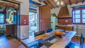 Una cocina rústica con una mesa de madera, un refrigerador y una lámpara colgante.