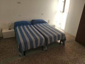 A bedroom with a bed, two bedside tables, a nightstand, and a window.
