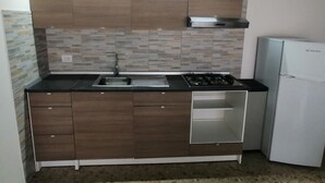 Eine kleine Küche mit Gasherd, Spüle und Kühlschrank.