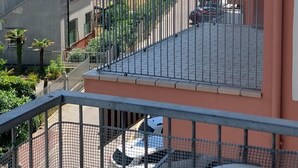 Ein Balkon mit Meerblick, ein Parkplatz und angrenzende Gebäude.