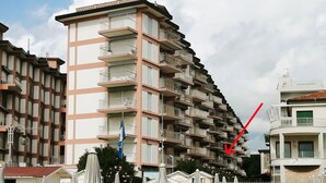 Ein mehrstöckiges Hotel mit Balkonen, Außenbestuhlung und einer Flagge.