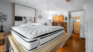 Une chambre à coucher avec un lit, une télévision, un miroir et une armoire en bois.