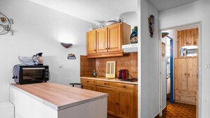 Une cuisine de taille réduite, dotée de meubles en bois, d’un four à micro-ondes et d’un évier.