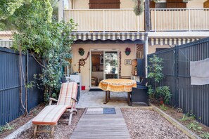 Un patio con tavolo e sedie, un pontile in legno e un giardino recintato.