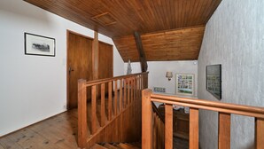 A wooden staircase with a railing, a wooden door, and a wall-mounted picture. - Holiday Home 'La Maison Bayle' with Mountain View, Private Garden & Wi-Fi (Mauvezin)