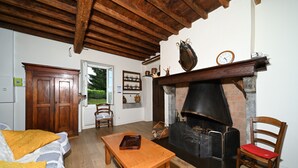 A cozy living room with a fireplace, wooden furniture, and a door leading to another room. - Holiday Home 'La Maison Bayle' with Mountain View, Private Garden & Wi-Fi (Mauvezin)