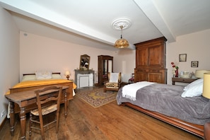 Um quarto com uma cama, escrivaninha, cadeira, lareira e guarda-roupa.
