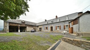 A courtyard with a car, stone walls, and a building with multiple windows and doors. - Holiday Home 'La Maison Bayle' with Mountain View, Private Garden & Wi-Fi (Mauvezin)