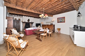 Uma área de jantar rústica com mobiliário de madeira, lareira e cozinha.